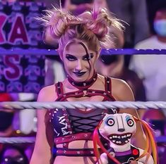 a female wrestler holding a stuffed animal in front of her face and other people behind her