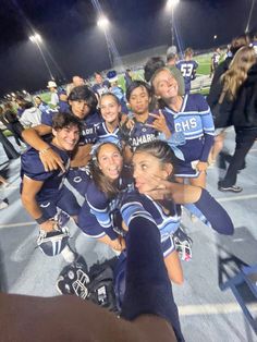 a group of young women standing on top of a field next to each other wearing blue uniforms