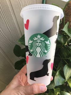 someone holding up a starbucks cup with dogs on the side and hearts painted on it