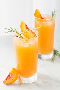 two glasses filled with orange juice, garnished with rosemary and sliced peaches