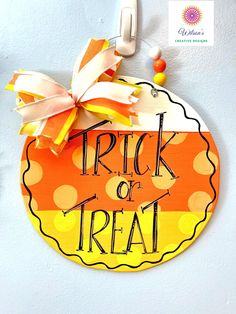 a trick or treat sign hanging on the side of a white wall with orange and yellow polka dots