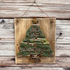 a wooden plaque with a christmas tree made out of branches and pine cones on it