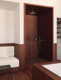 a bath room with a couch a shower and a book shelf on the wall in it