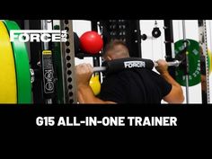 a man in black shirt lifting a barbell at the force 5 gym with green and red balls behind him