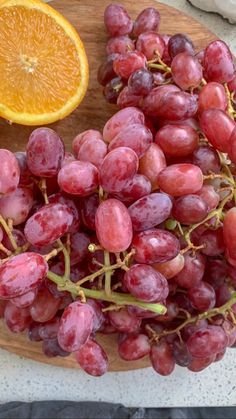 a wooden plate topped with grapes and an orange