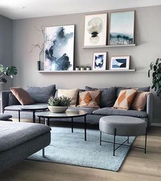 a living room with grey couches and pictures on the wall above them, along with a blue rug