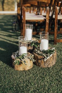 candles are placed on logs in the grass at an outdoor wedding ceremony with greenery