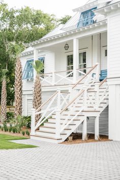 a white house with blue shutters and palm trees