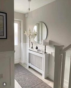 a white bathroom with a sink and mirror on the wall next to a rug that has flowers in it