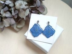 Adorn your ears with the timeless beauty of #nature through these exquisite #handmadestudearrings - #Hydrangeas are known for their delicate and abundant blossoms, symbolizing #grace and #beauty - These #flowers also represent #love #harmony and #peace conveying sincere emotions, #gratitude and deep understanding - #studearrings #realflowers #resin #resinjewelry #handmade #jewelry #naturelovergift #giftidea #stud #hydrangeaflowers #hydrangeaearrings #botanicalearrings #natureinspiredjewelry Nature-inspired Jewelry Ear Wire For Gift, Nature-inspired Teardrop Earrings For Gifts, Elegant Pressed Flowers Earrings For Mother's Day, Nature-inspired Flower Earrings With Birth Flower For Gift, Nature-inspired Flower Earrings For Birth Flower Gift, Handmade Nature-inspired Earrings As A Gift For Her, Mother's Day Gift Pressed Flower Earrings, Nature-inspired Drop Earrings With Birth Flower, Dangle Flower Earrings With Natural Inclusions As Gift