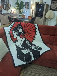 a red couch with a white and black blanket on it in a room filled with furniture