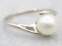 This beautiful, bypass-designed white gold ring is an amazing and feminine statement ring! The big, luscious pearl is cultured, measuring 7.7mm round and with lovely, soft pink iridescence. This would make a perfect piece as a right-hand ring on a Wedding Day - something that could be worn over and over for years to come.Metal: 14K White GoldGem: PearlGem Measurements: 7.4 mm, RoundRing Size: 9.50Marks: "\S/ 14K" Stamped on the inside band Elegant Bypass Ring With Tension Setting For Formal Occasions, Elegant White Gold Bypass Ring, Elegant White Bypass Ring, Classic Round Bypass Ring With Tension Setting, Elegant Polished Bypass Ring For Anniversary, Classic White Bypass Ring For Formal Occasions, Elegant Silver Bypass Ring For Formal Occasions, Elegant Silver Bypass Ring For Formal Events, Elegant Bypass Ring With Round Band For Anniversary