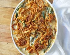 a casserole dish with onion rings and green beans in it on a wooden table