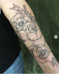 a woman's arm with flowers and leaves tattooed on the wrist, in black ink