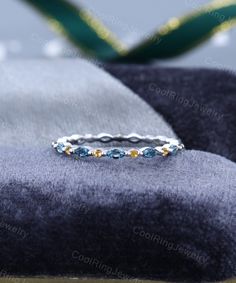 an image of a wedding ring with blue and yellow stones on it's side