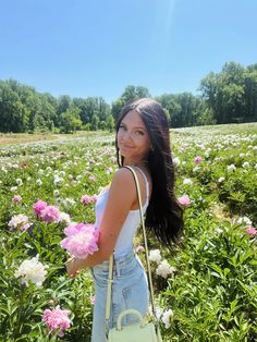 a woman standing in a field with pink flowers