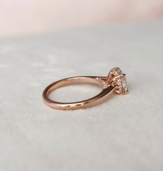 a close up view of a diamond ring on a white surface with light colored background