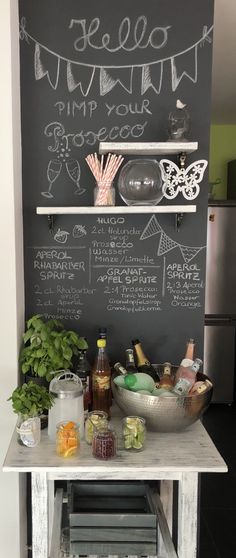 a chalkboard is on the wall behind a small table with drinks and condiments