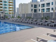 an outdoor swimming pool with lounge chairs and umbrellas next to the building's windows