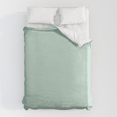 an unmade bed with two pillows and a green comforter on the bottom half