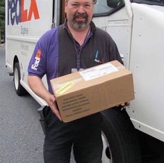 a man standing next to a delivery truck holding a box