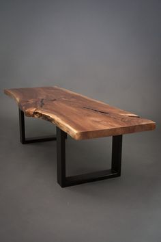 a wooden table sitting on top of a gray floor next to a black metal frame