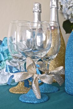 there are three wine glasses on the table with blue and gold decorations around them,