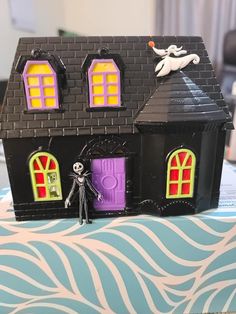 a toy house with a skeleton on the front door and windows painted purple, yellow and orange