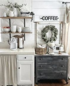 a kitchen with white cabinets and shelves filled with coffee accessories, wreaths and other items