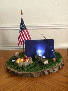 an american flag is placed on top of a small tree stump with rocks and candles