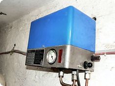 a blue box mounted to the side of a white wall next to a light bulb