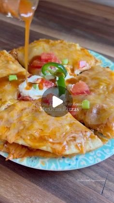 someone is pouring sauce on some quesadillas that are sitting on a blue and white plate