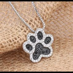 a dog paw necklace with black and white crystals