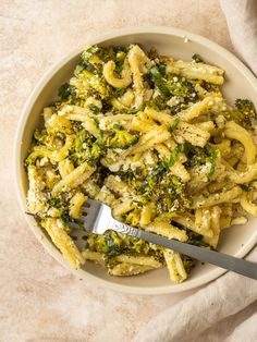 a bowl filled with pasta and broccoli on top of a white table cloth