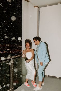 a man and woman standing next to each other in front of a window with rain falling on them