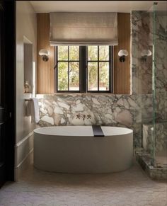 a bathroom with marble walls and flooring on the wall, along with a large bathtub