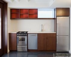 an empty kitchen with stainless steel appliances and wood cabinets