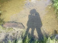 the shadow of a person standing in shallow water