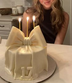 a woman sitting in front of a cake with lit candles