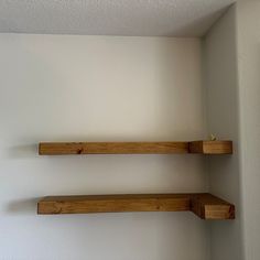 two wooden shelves in the corner of a room