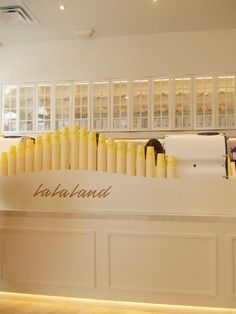 the interior of a restaurant with white walls and yellow candles on the counter, along with shelves