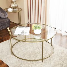 a glass table sitting on top of a wooden floor next to a couch and chair