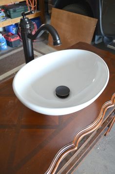 a white sink sitting on top of a wooden counter next to a faucet