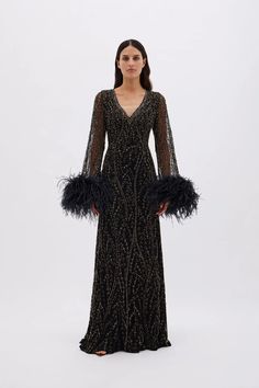 Description: The Nowa gown is other-worldly, sourcing inspiration from vast starry skies. Dreamt from tulle, it’s sprinkled with scintillating embellishment achieved by hand. The abundance of floaty feathers recall the indisputable glamour of silver-screen sirens.  Hand-placed embellishment Ostrich feathers at cuffs V