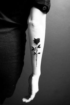 a black and white photo of a woman's arm with a rose tattoo on it