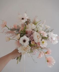 a woman holding a bouquet of flowers in her hand with white and pink blooms on it