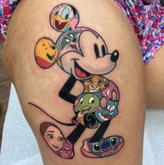 a cartoon mickey mouse tattoo on the back of a woman's thigh, with various characters