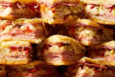 a pile of ham and cheese pastries stacked on top of each other with toppings