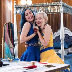 two young women hugging each other in front of a bed with an ornate headboard