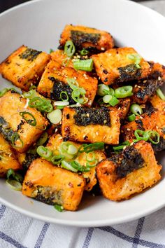 a white bowl filled with tofu and green onions